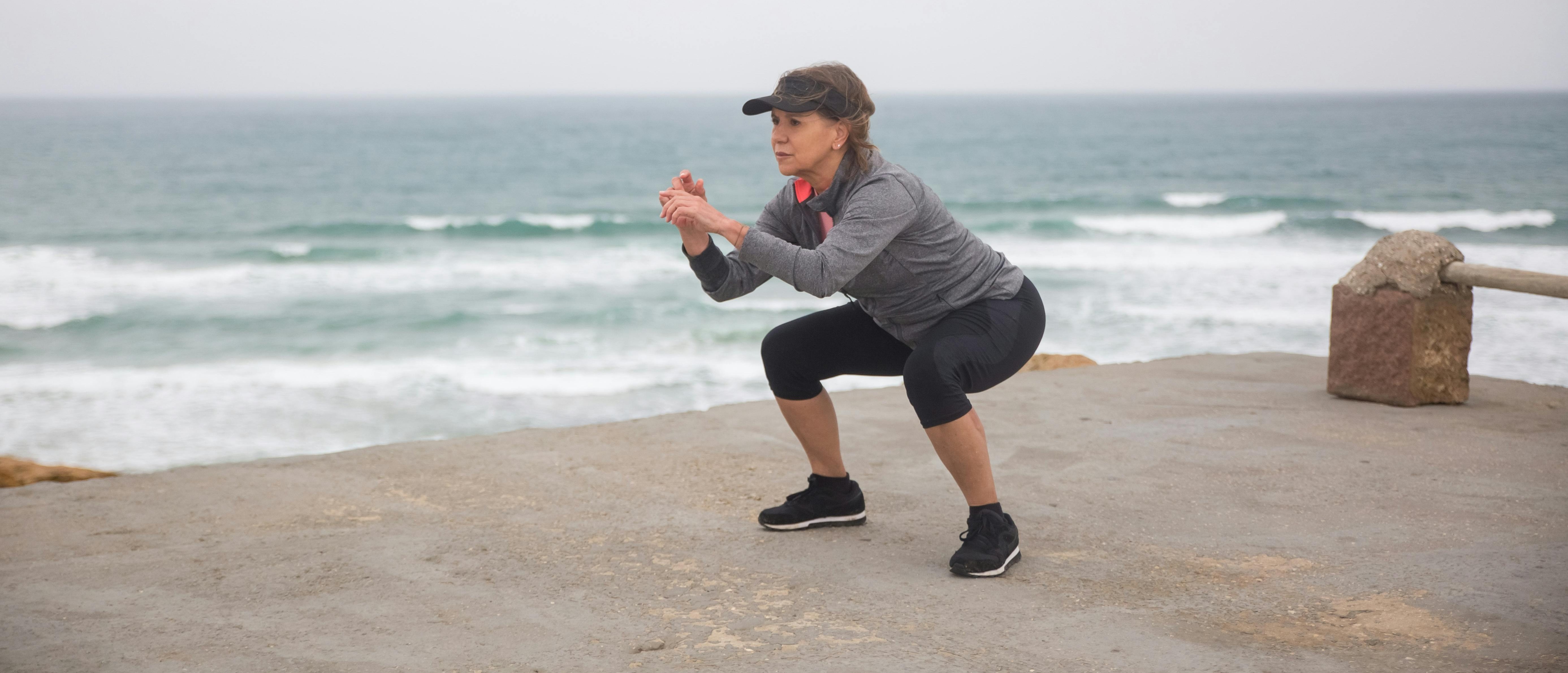 Woman in athletic wear performs a squat on a concrete surface